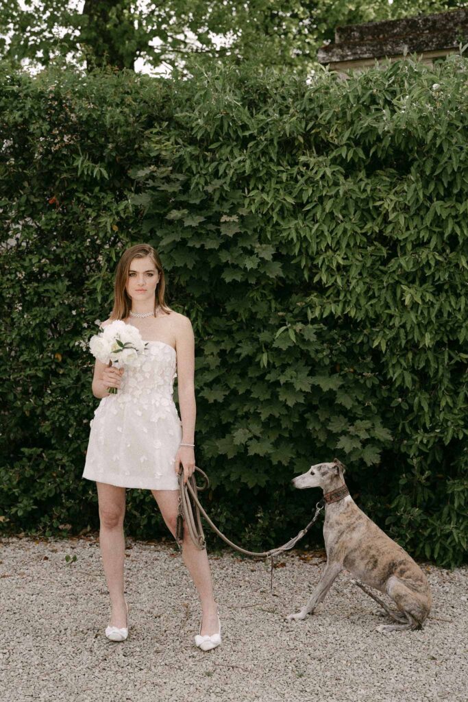 Chateau sainte claire keith flament bride short lace dress holding bouquet and dog