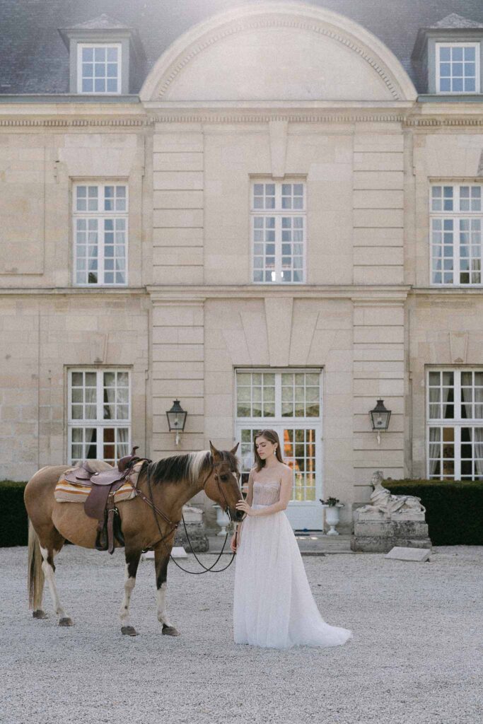 Chateau sainte claire keith flament bride strapless corset tulle dress holding horse venue building background