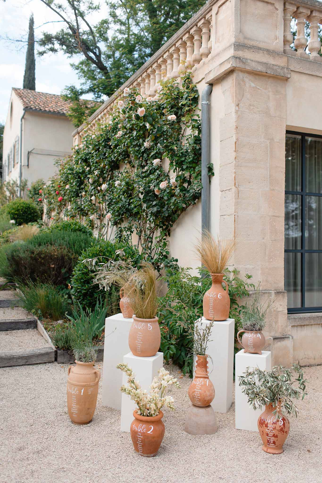 Rustic terracotta seating card display with dried grasses at Mediterranean courtyard wedding venue