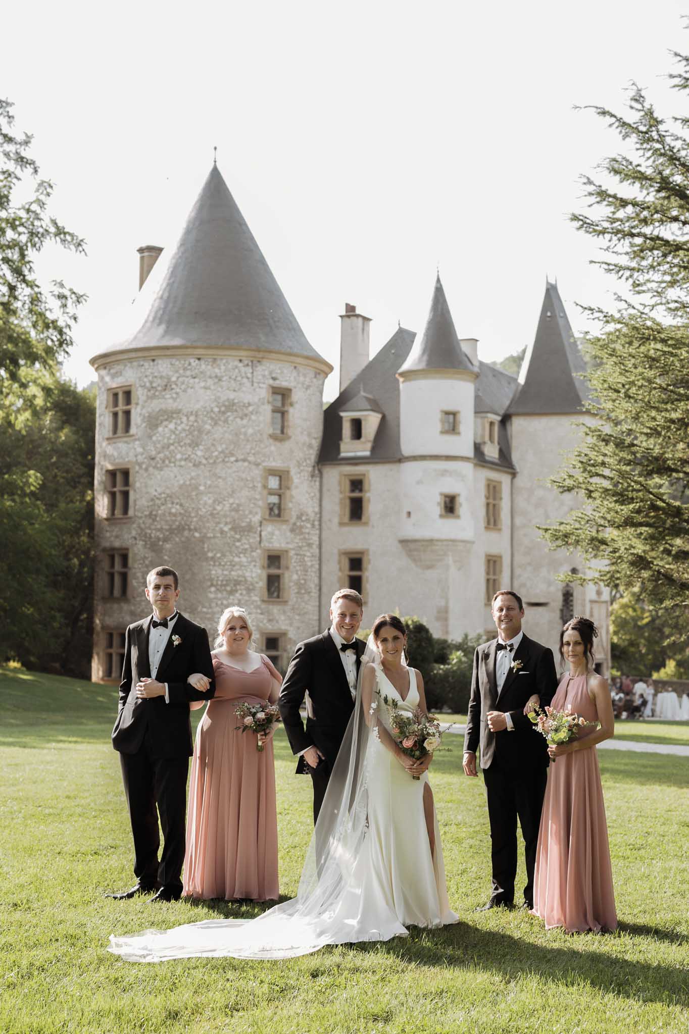 Bridal party portrait with bride, groom and wedding party on lawn in front of stone chÃƒÂ¢teau with turrets