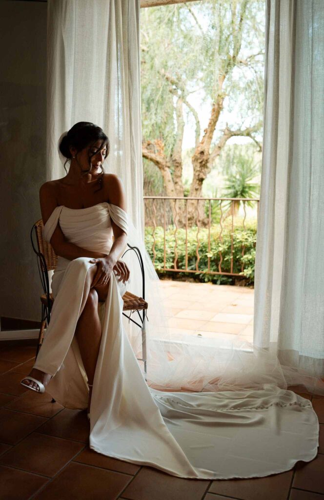 manoir de letang myrto events bride getting ready sitting long trail dress window