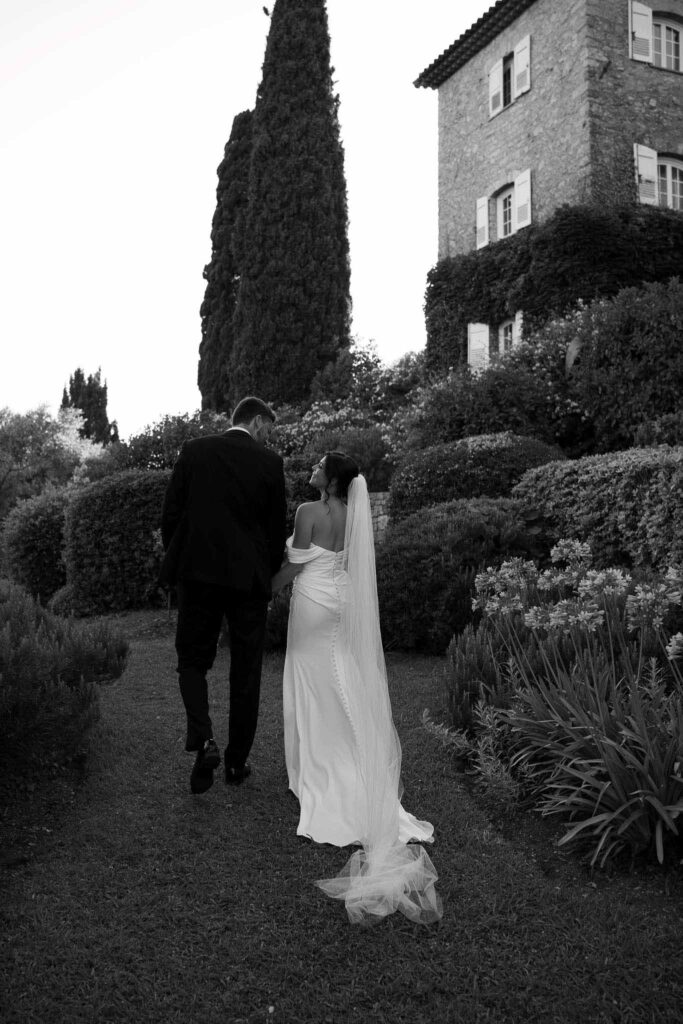 manoir de letang myrto events bride groom holding hand looking each other walking garden black white photo