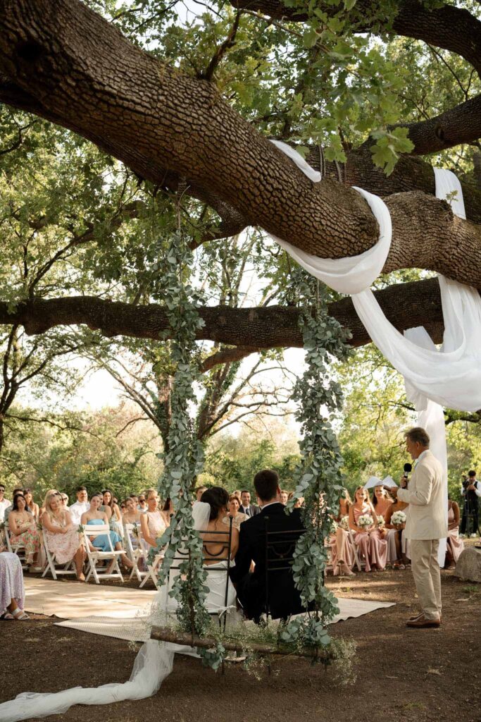 manoir de letang myrto events ceremony proper bride groom guests seated officiant under tree altar
