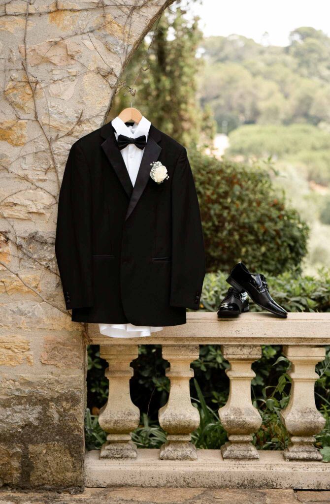 manoir de letang myrto events detail shot black tuxedo shoes hanging stone arch garden area