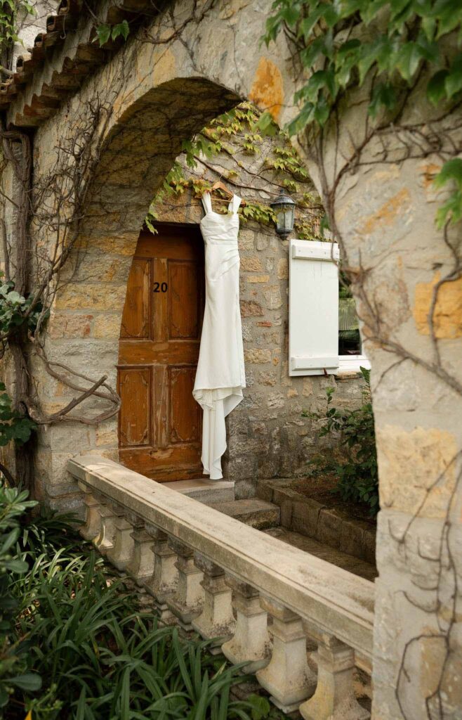 manoir de letang myrto events detail shot bride dress hanging by the garden stone wall