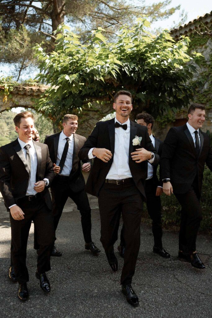 manoir de letang myrto events groom groomsmen walking holding tuxedo garden