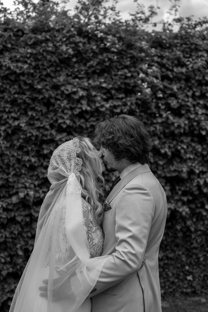 MCaelicia Galinier Lourmarin bride groom hug kiss grass wall background