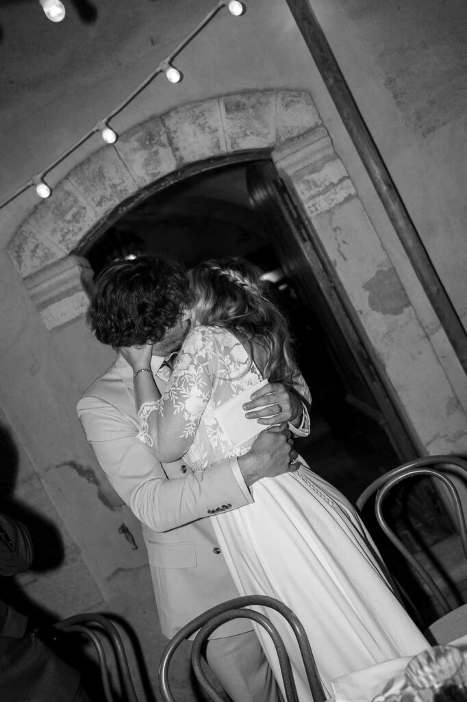 MCaelicia Galinier Lourmarin bride groom kissing hug reception black white photo