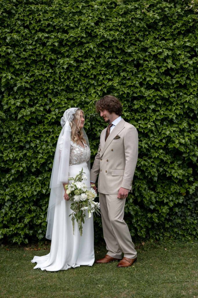 MCaelicia Galinier Lourmarin bride groom looking each other grass wall background