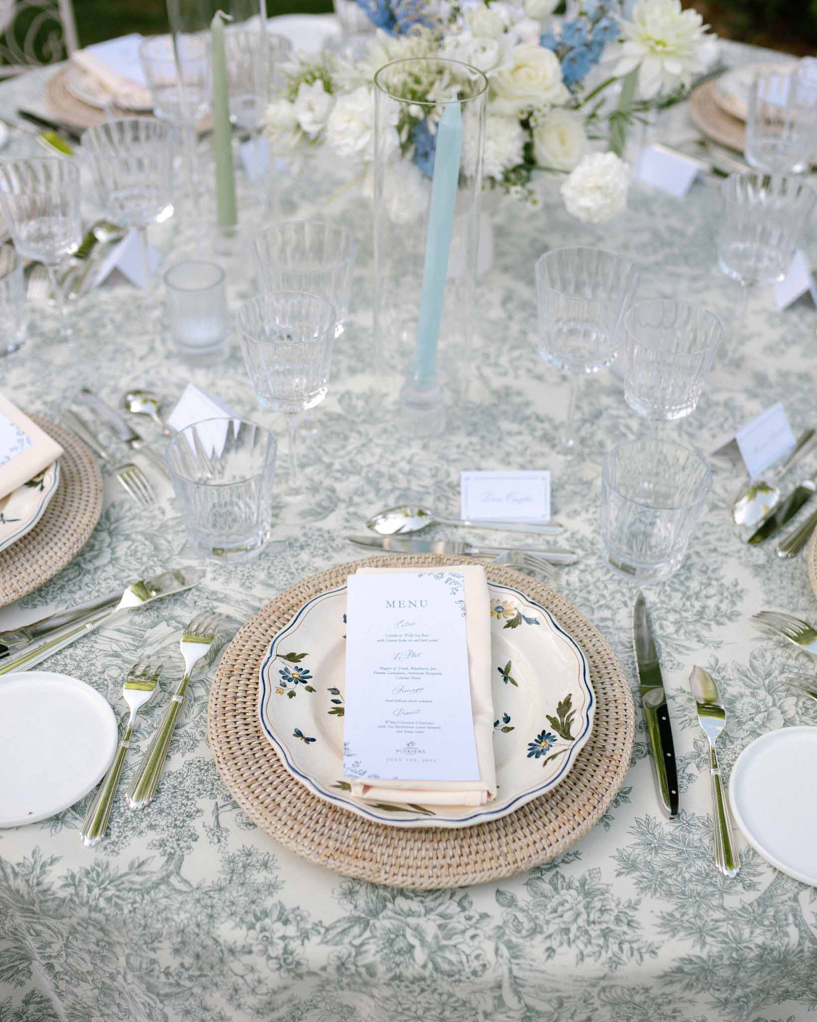 Sage toile place setting with botanical plate, blush napkin, and white peony and blue delphinium centerpiece