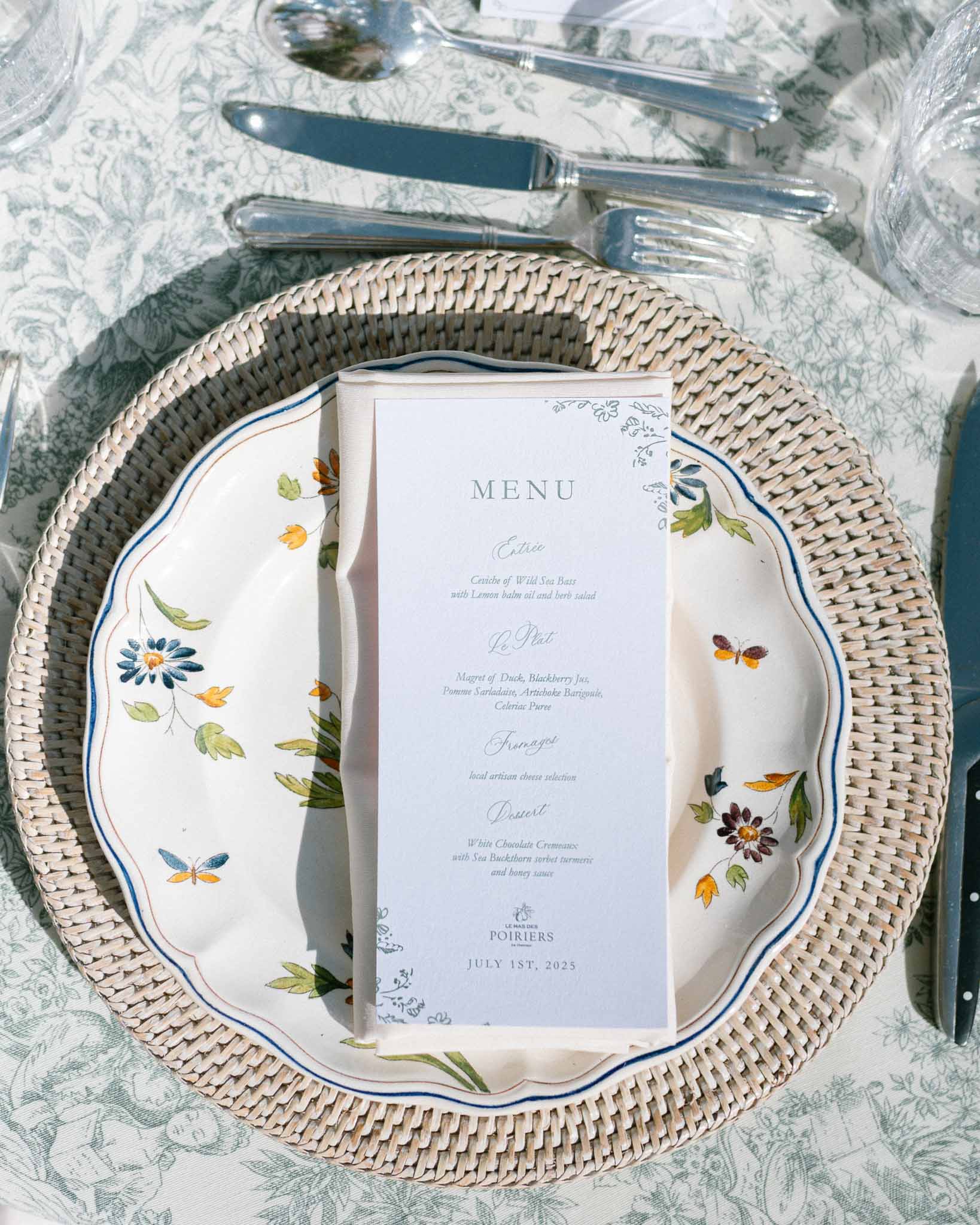 Hand-painted botanical dinner plate with blue rim on sage toile linen with printed French menu card