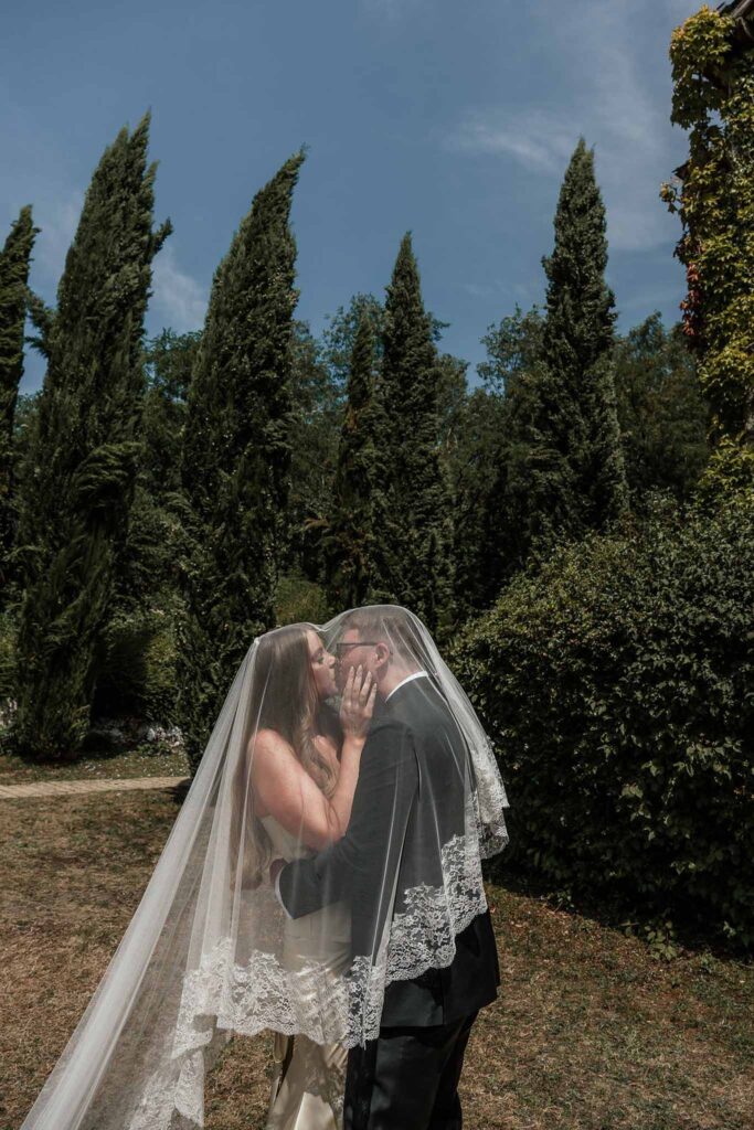 du Raysse W.Towell bride groom kissing inside veil garden