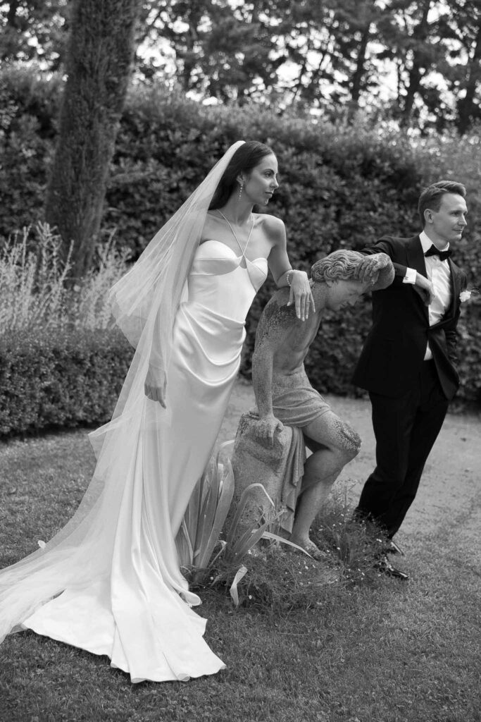 Laurence Weds in May couple leaning beside vintage statue garden