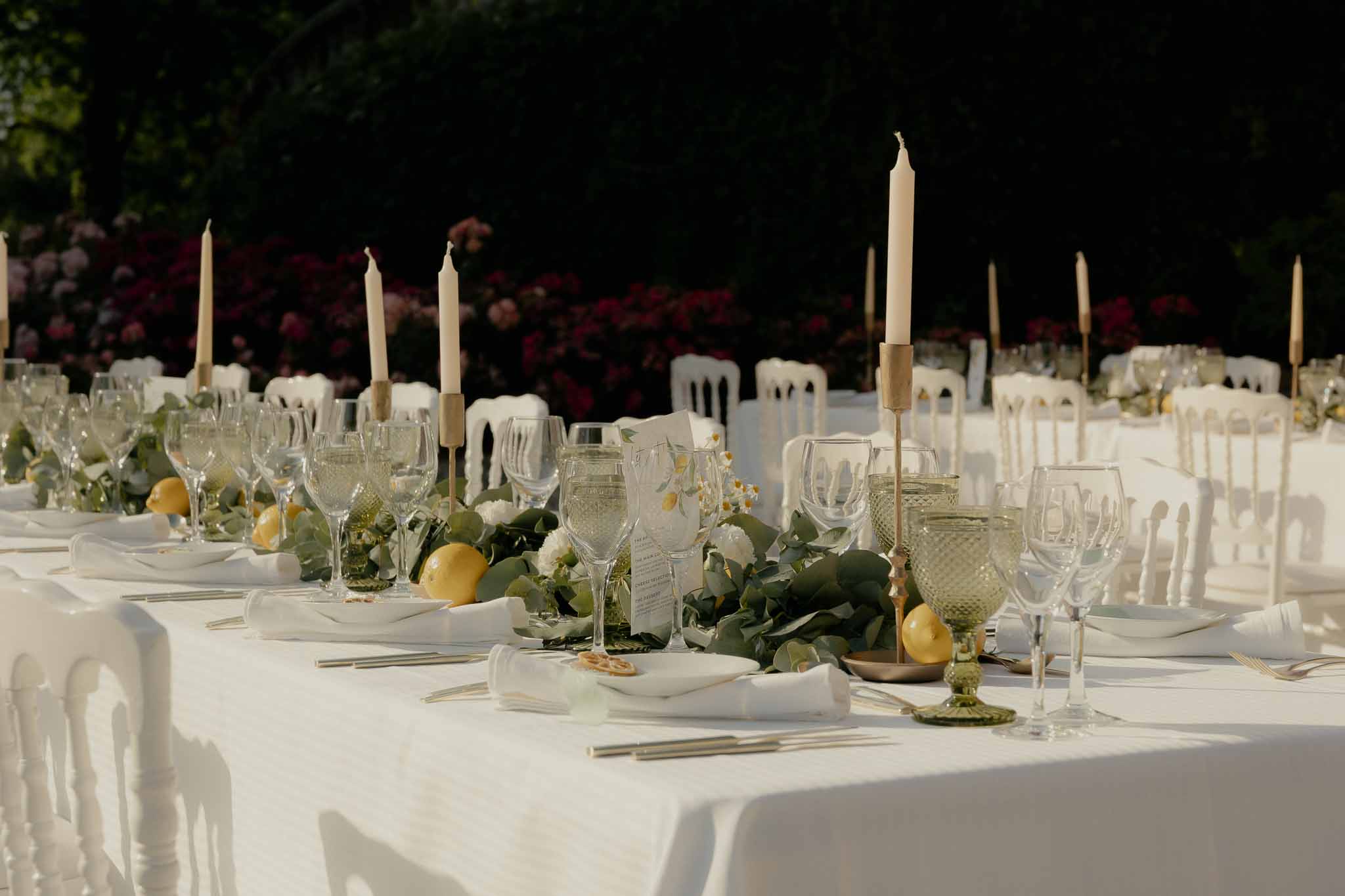 Reception table with lemon and eucalyptus garland runner, gold candlesticks, and green goblets