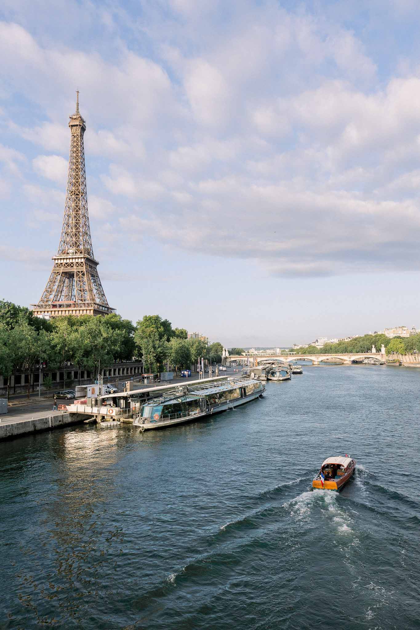 Seine River view with Eiffel Tower, Haussmann buildings, moored glass barge, and passing motorboat