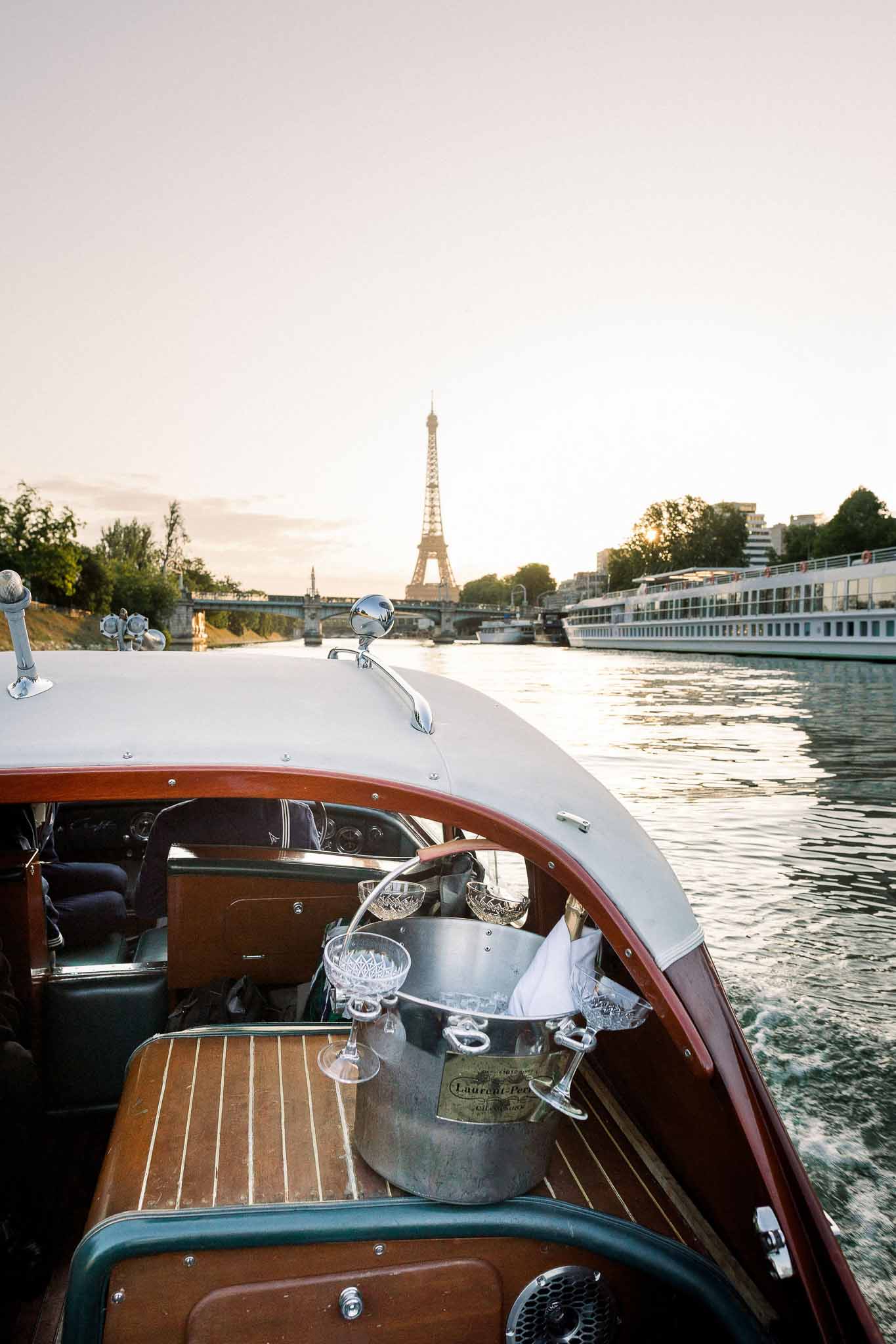 Champagne coupes and Laurent-Perrier bucket on vintage wooden boat cruising the Seine past Eiffel Tower