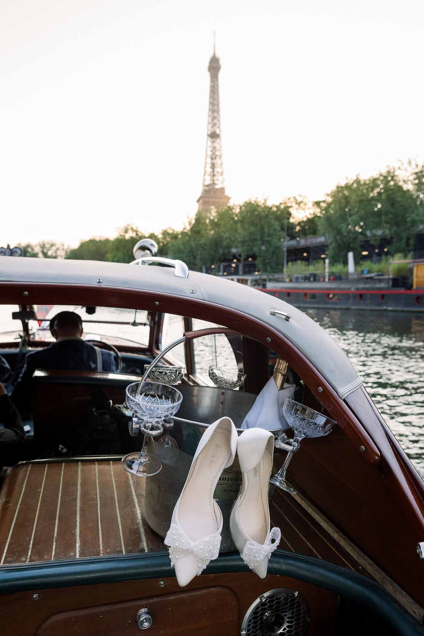 Pearl-embellished bridal flats with champagne bucket on vintage wooden boat with Eiffel Tower in background