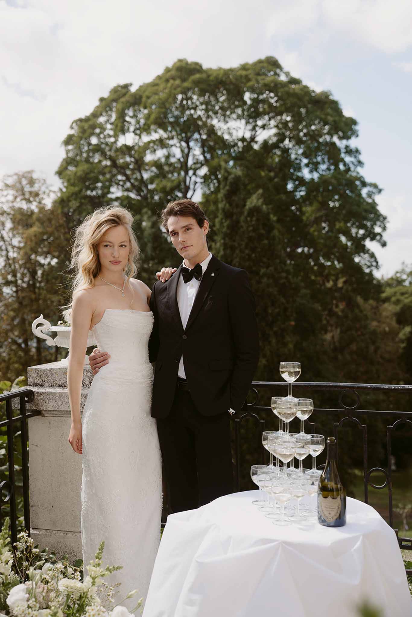 Couple on stone terrace beside Dom Perignon champagne tower of coupe glasses