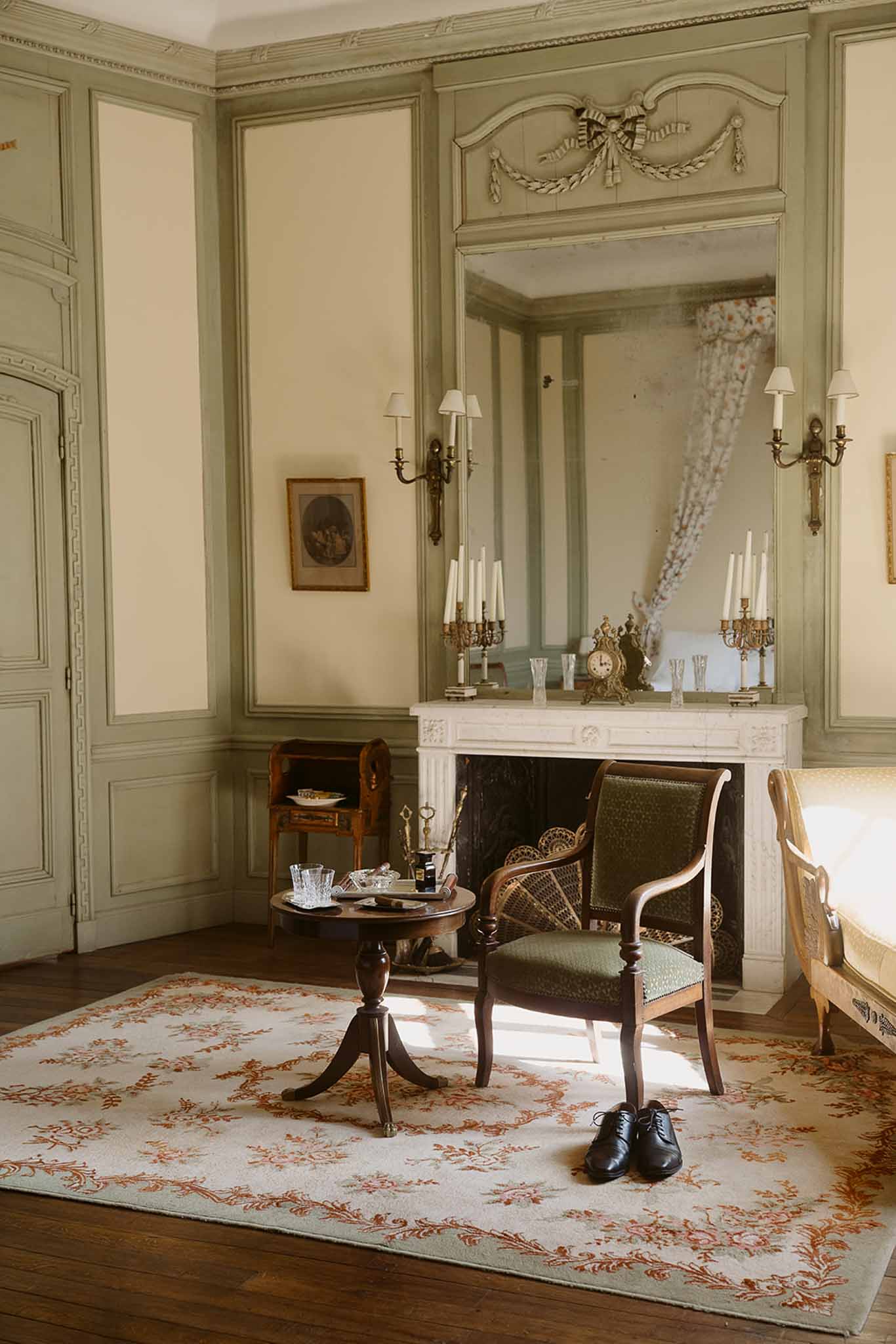 Groom's black Oxford shoes on Aubusson rug in sage green paneled chateau salon with marble fireplace and gilt mirror