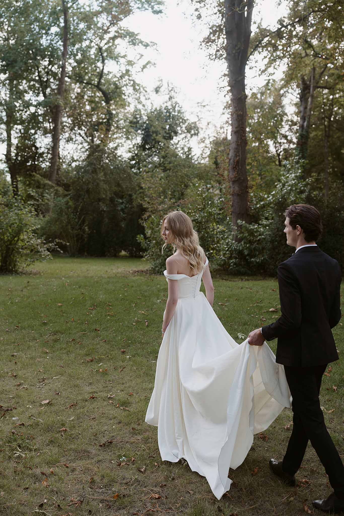 Bride and groom walking hand in hand in a garden