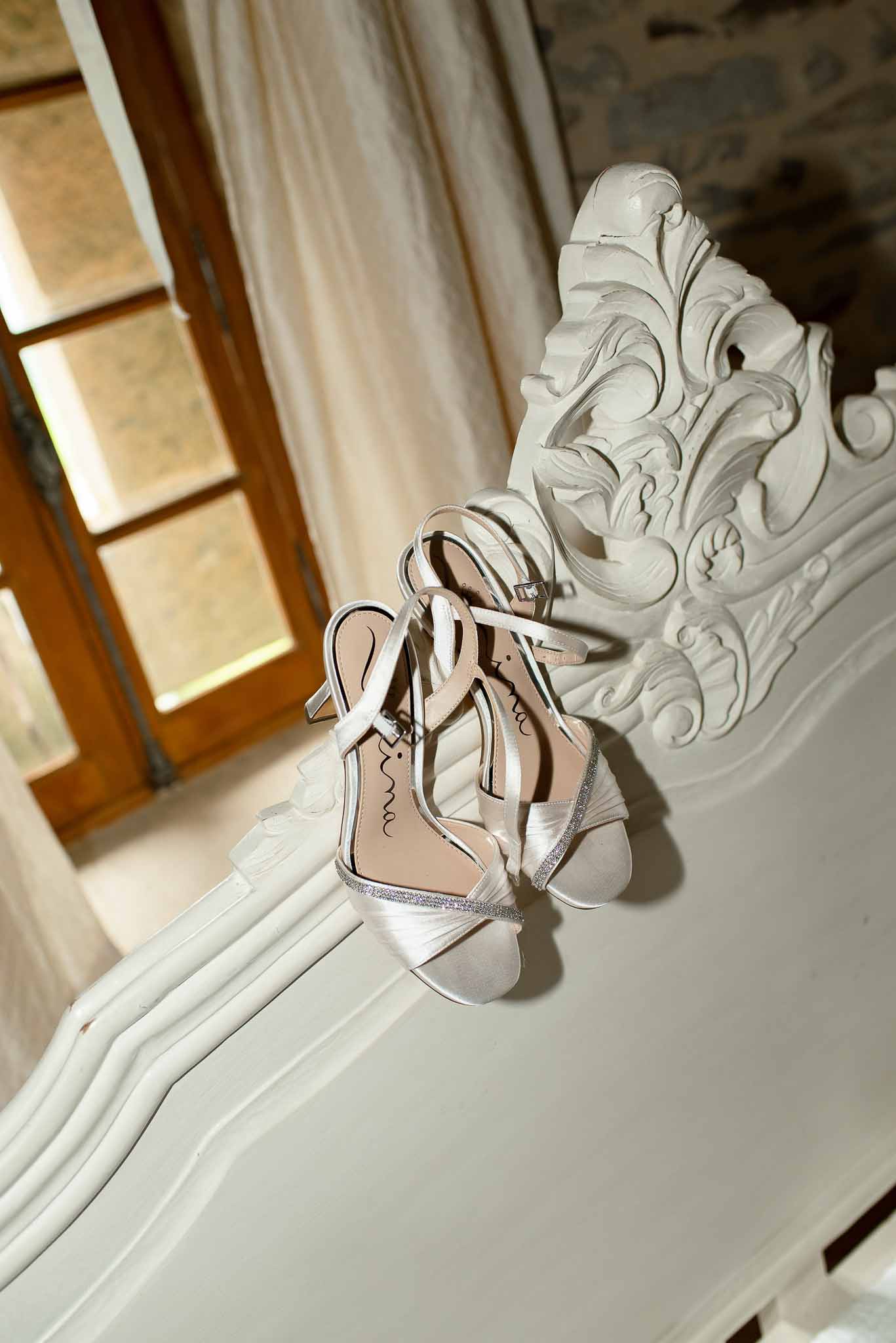 Ivory satin bridal heeled sandals with silver glitter trim on ornate white fireplace mantel